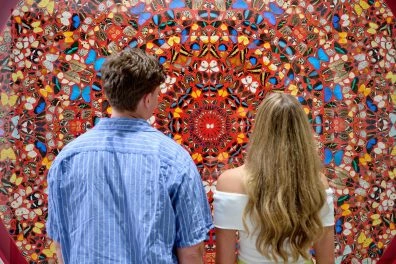 Couple admiring colorful butterfly wall installation by Hirst at Moco Museum London