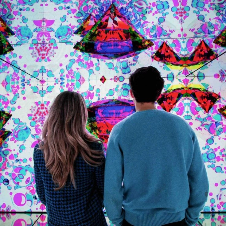 Couple admiring immersive digital art wall at Moco Museum Amsterdam.